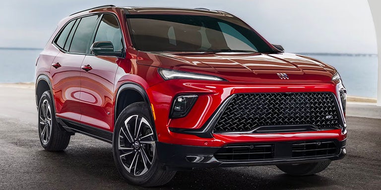 Three-Quarters View of a Red 2025 Buick Enclave ST with a Lake Nearby